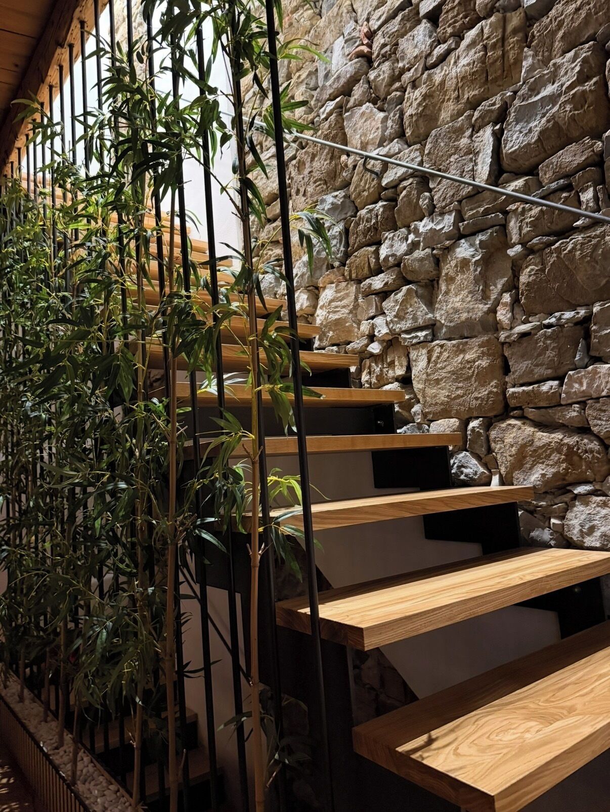 A staircase with wooden steps and a stone wall backdrop.