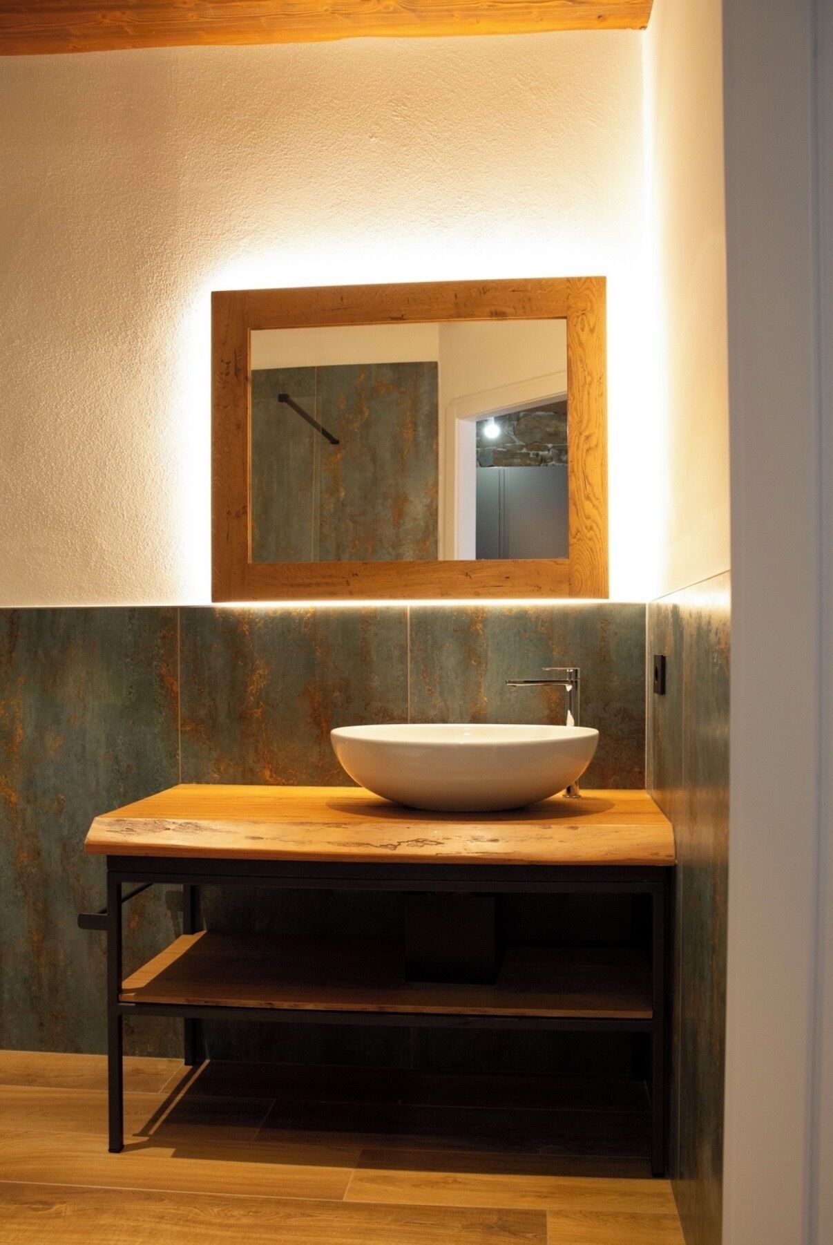 Une salle de bain avec un meuble-lavabo en bois, un lavabo sur colonne et un miroir au-dessus.