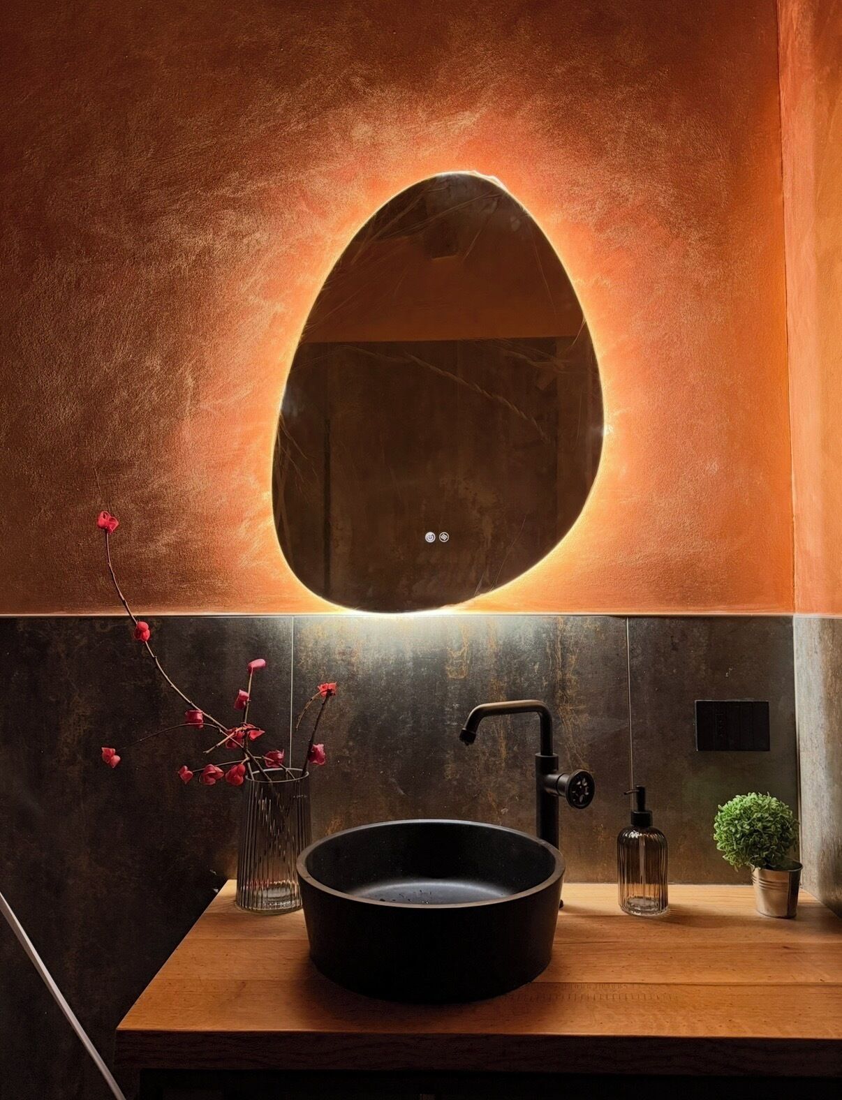 A bathroom with a round mirror, a sink, a faucet, and a potted plant.