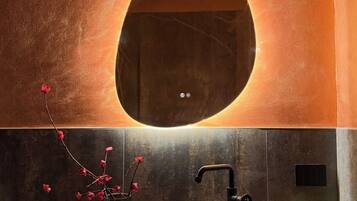 A bathroom with a round mirror, a sink, a faucet, and a potted plant.