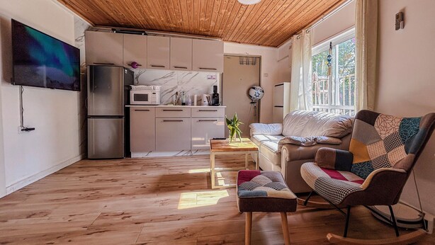 Un espacio habitable compacto con cocina, sofá, mecedora y televisor.