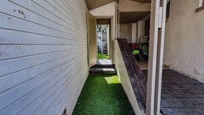 Un pasillo estrecho con paredes de madera y un camino de césped artificial verde.