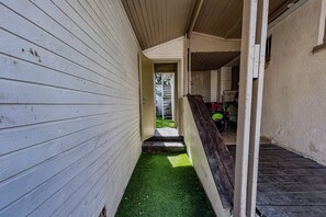 A narrow corridor with wooden walls and a green artificial turf path. - Bright 2BR Home with Private Garden and Free Parking (Herzliya)