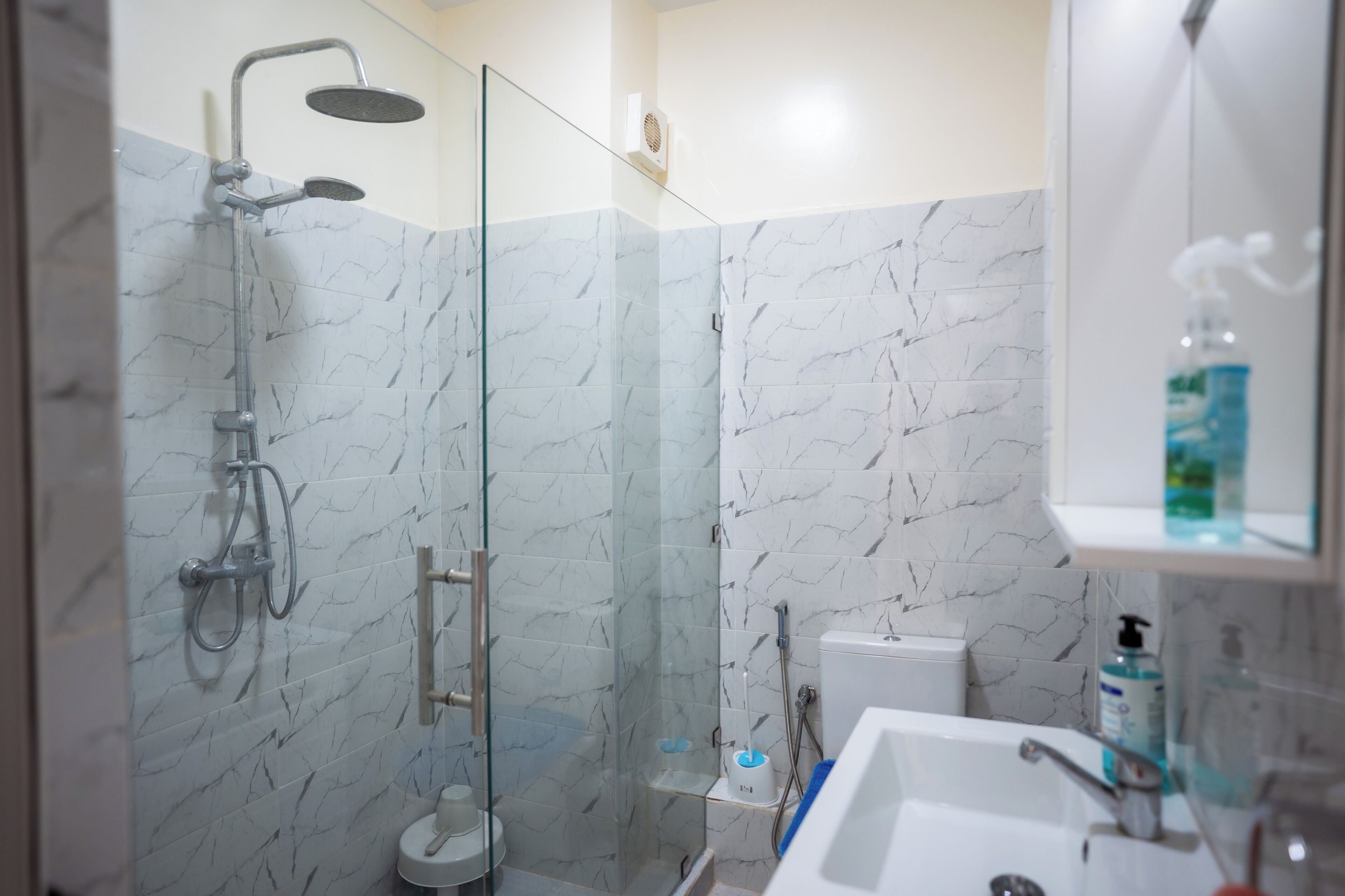 A modern bathroom with a glass-enclosed shower, a toilet, and a sink.