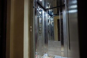 Interno di un ascensore con pannelli di controllo e pulsanti di emergenza.