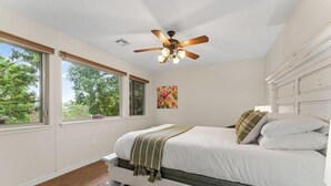A bedroom with a bed, a ceiling fan, a window, and a painting on the wall. - Four Bedroom Home with War Eagle River View and Access (Rogers)