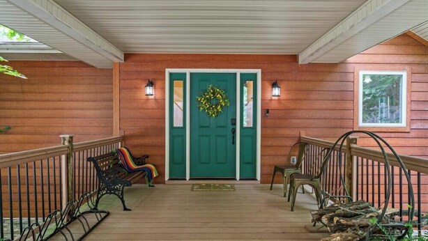 A wooden porch with a green door, two benches, and a railing. - Four Bedroom Home with War Eagle River View and Access (Rogers)