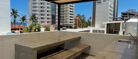 An outdoor patio area with a concrete table and bench, surrounded by a pergola.