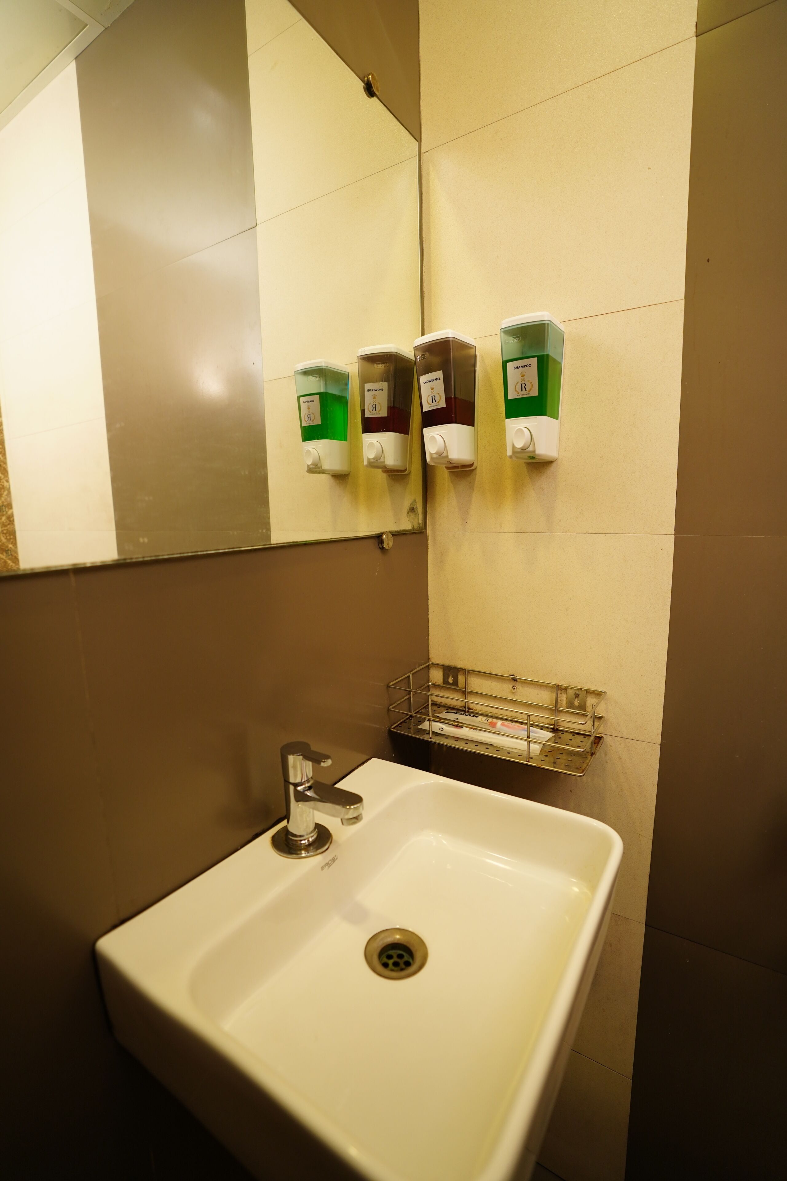 Un baño con un lavabo blanco, un espejo y dispensadores de jabón.