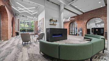 A modern lounge area with a curved green sofa, a flat-screen TV, and a fireplace.