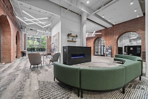 Un salon moderne doté d’un canapé vert aux lignes arrondies, d’un téléviseur à écran plat et d’une cheminée.