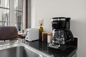 Une cuisine équipée d’une machine à café, d’un grille-pain et d’une bouteille d’huile d’olive posée sur le comptoir.