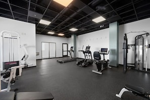 A gym with cardio machines, weightlifting equipment, and a mirrored wall.