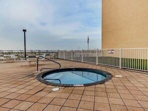 A rooftop pool area with a hot tub, surrounded by a white fence, and a view of the city skyline. - Surfside Shores I 1801 by ALBVR - Beautiful Beachfront Corner Condo (Gulf Shores)