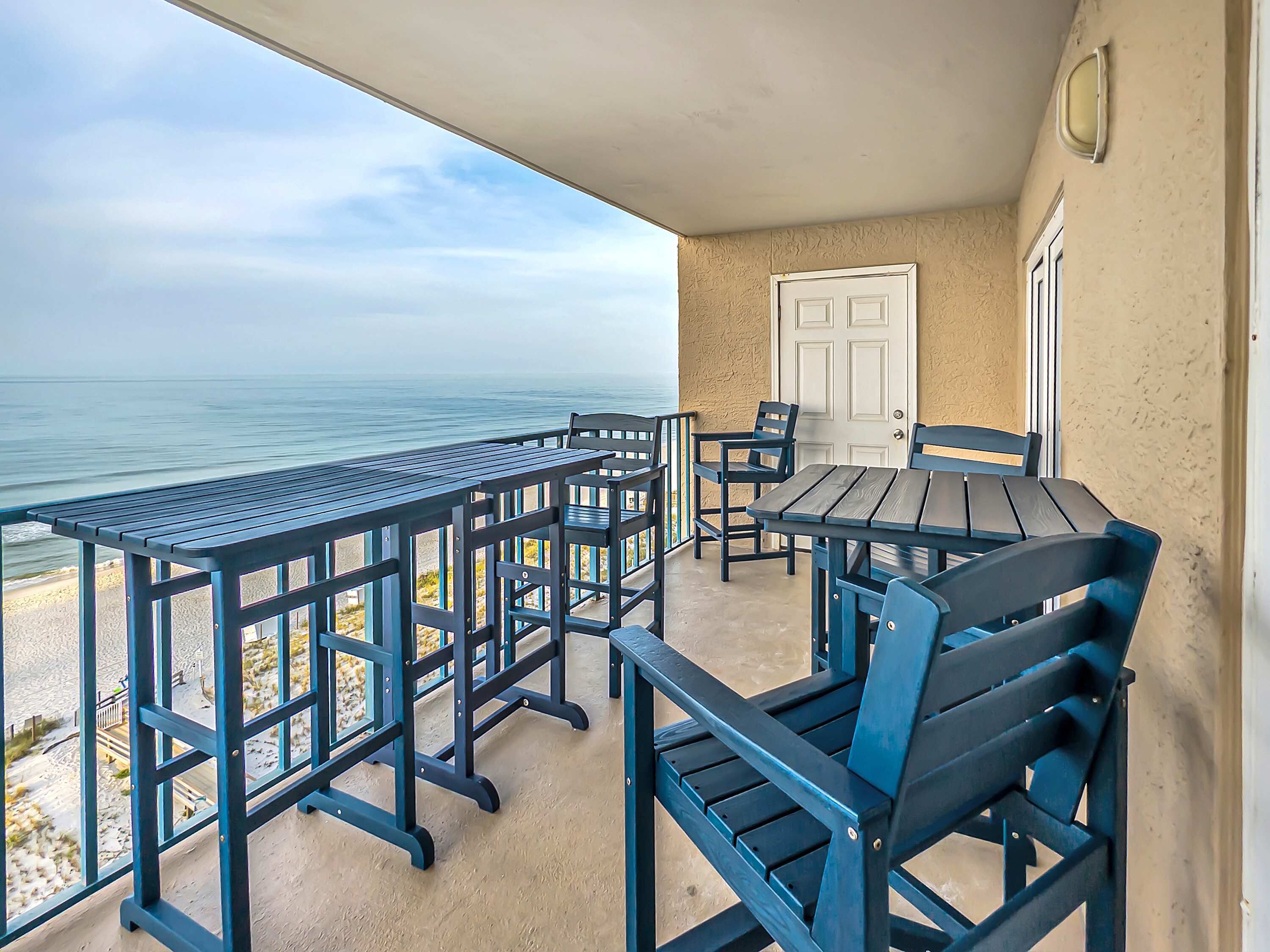 A balcony with a view of the ocean, featuring a table and chairs.