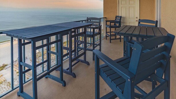 Een balkon met uitzicht op de oceaan, voorzien van een tafel en stoelen.