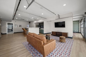 A spacious living area with a sofa, ottoman, and a flat-screen TV.