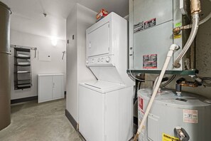 Une buanderie équipée d’un lave-linge et d’un sèche-linge, d’un meuble de rangement et d’un chauffe-eau.