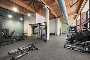 Une salle de sport équipée de divers appareils d’exercice, notamment un tapis de course, des appareils de musculation et un support à squats.