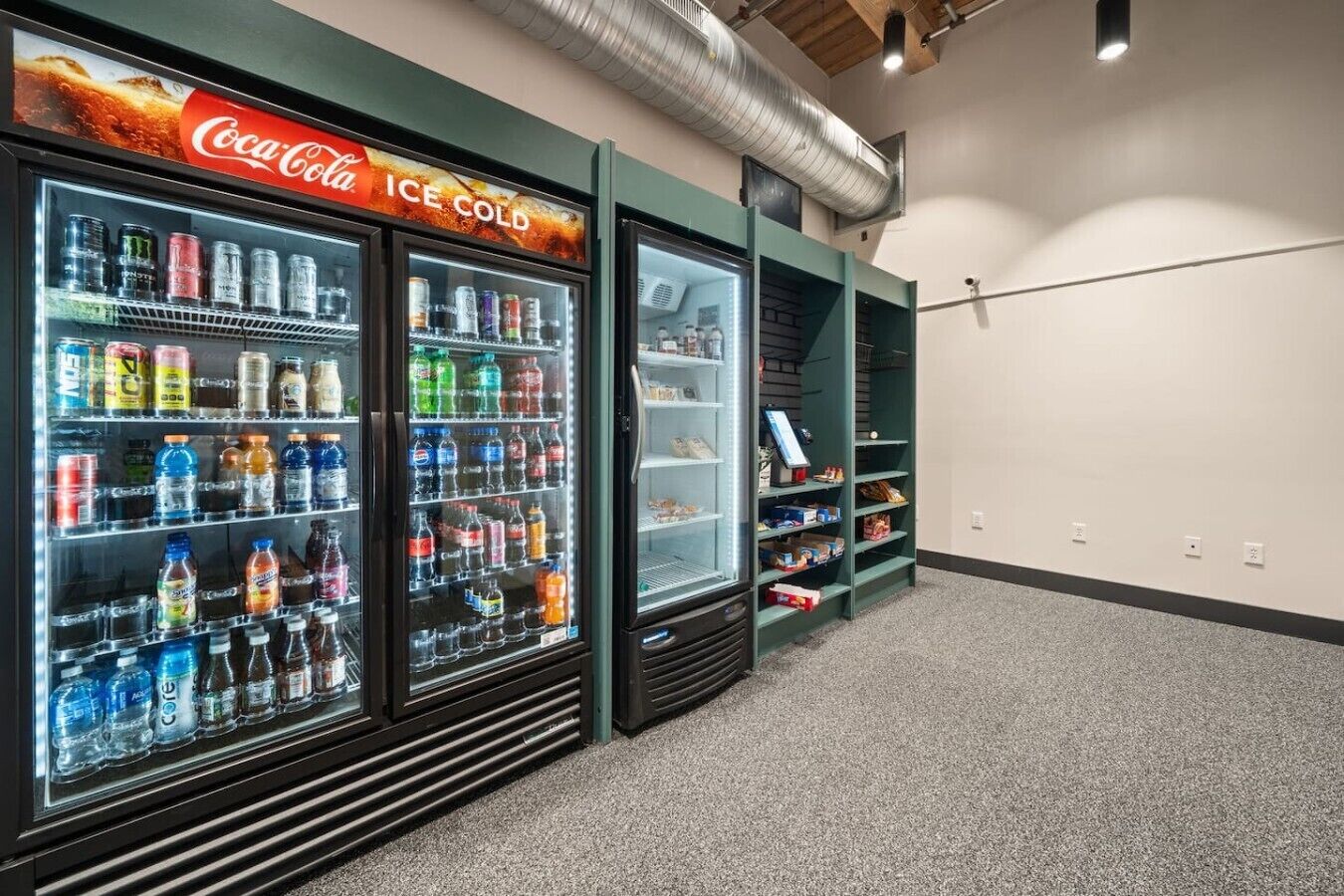 A vending area with Coca-Cola and other beverage dispensers, a shoe rack, and a checkout counter.