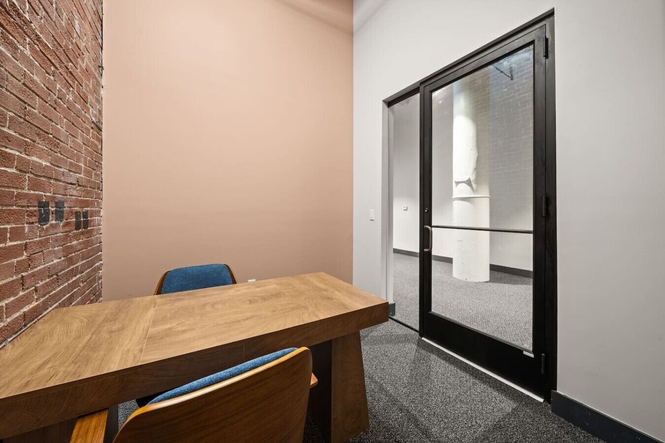 Un salón de conferencias con una mesa de madera, sillas y una pared de ladrillo.