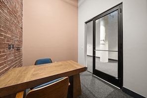 A conference room with a wooden table, chairs, and a brick wall.