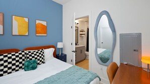 Quarto de hotel com uma cama, uma mesa, uma cadeira, um banheiro e um espelho.