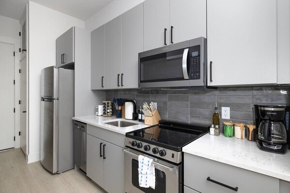 A modern kitchen with stainless steel appliances, including a refrigerator, microwave, stove, and dishwasher.
