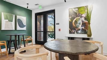 Ein Zimmer mit einem runden Tisch, Holzstühlen, einer grünen Wand und Kunstwerken.