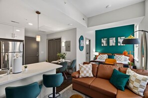 Um espaço de estar moderno com cozinha, sala de jantar e um quarto com parede de destaque em tom de verde-água.