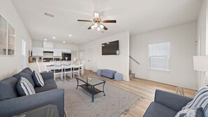 A modern living room with a sofa, coffee table, and a dining area with chairs. - Cozy Family Home, Prime Location Near Downtown (Galveston)