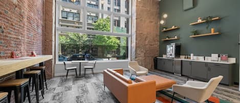 Un interior moderno con pared de ladrillo, ventanas amplias, zona de cocina y arreglos de asientos.