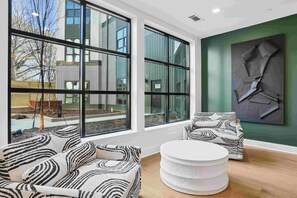 Un intérieur moderne avec de grandes fenêtres, une table ronde blanche et des canapés à motifs.