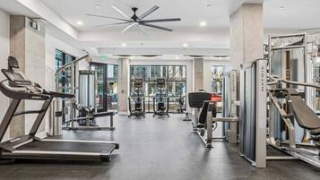A gym with cardio equipment, weight machines, and a ceiling fan.