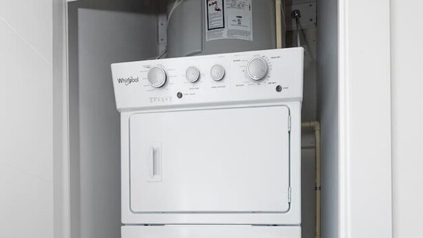 Máquina de lavar e secar compacta, branca e empilhada, num espaço reduzido.