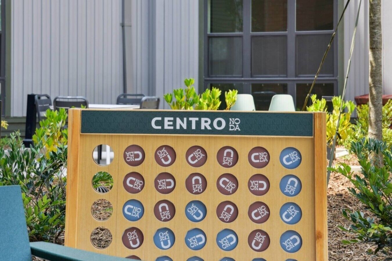 A wooden board game with the word 'CENTRO' at the top, surrounded by greenery.