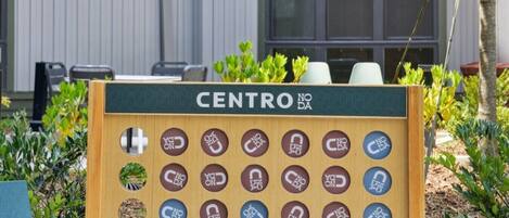 A wooden board game with the word 'CENTRO' at the top, surrounded by greenery.