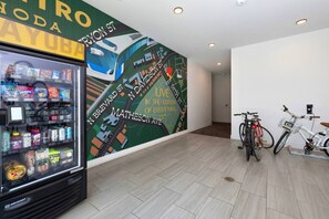 Un distributeur automatique rempli d’en-cas et une fresque murale représentant un paysage urbain avec un vélo.