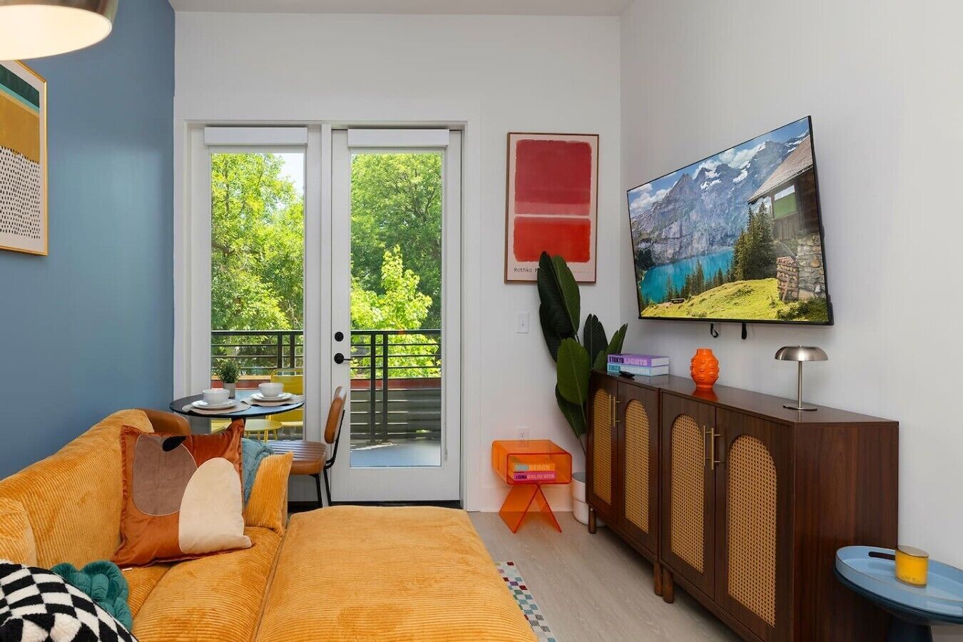 A living room with a sofa, a television, a cabinet, and a balcony with a door.