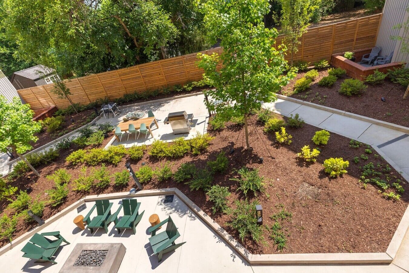 Ein angelegter Garten mit einer Terrassenfläche, Gartenmöbeln und einem Holzzaun.