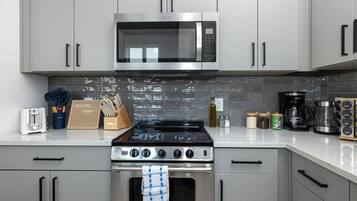 Una cocina moderna con electrodomésticos de acero inoxidable, gabinetes grises y salpicadero de azulejos.