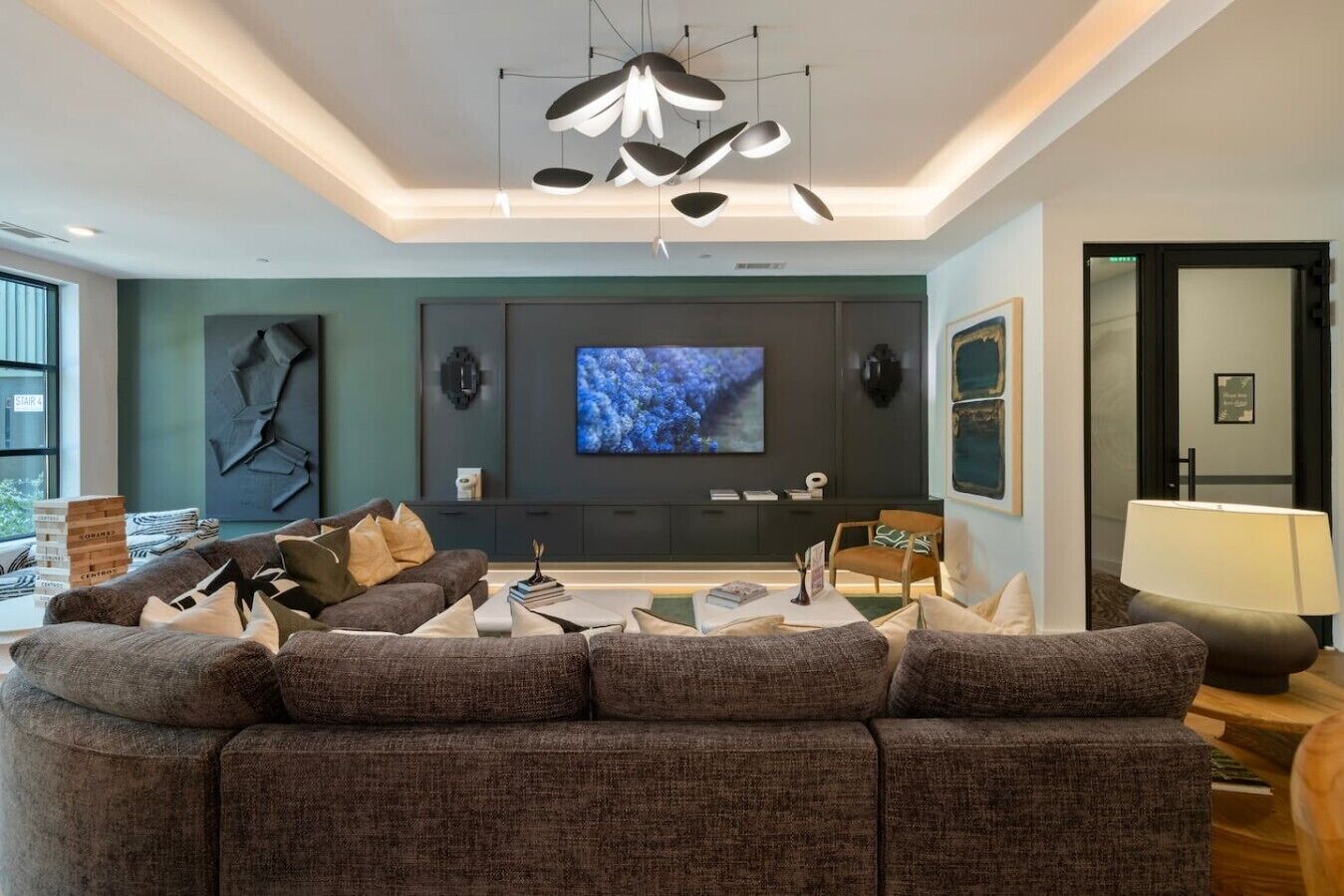 A modern living room with a sectional sofa, a flat-screen TV, and a unique ceiling light fixture.