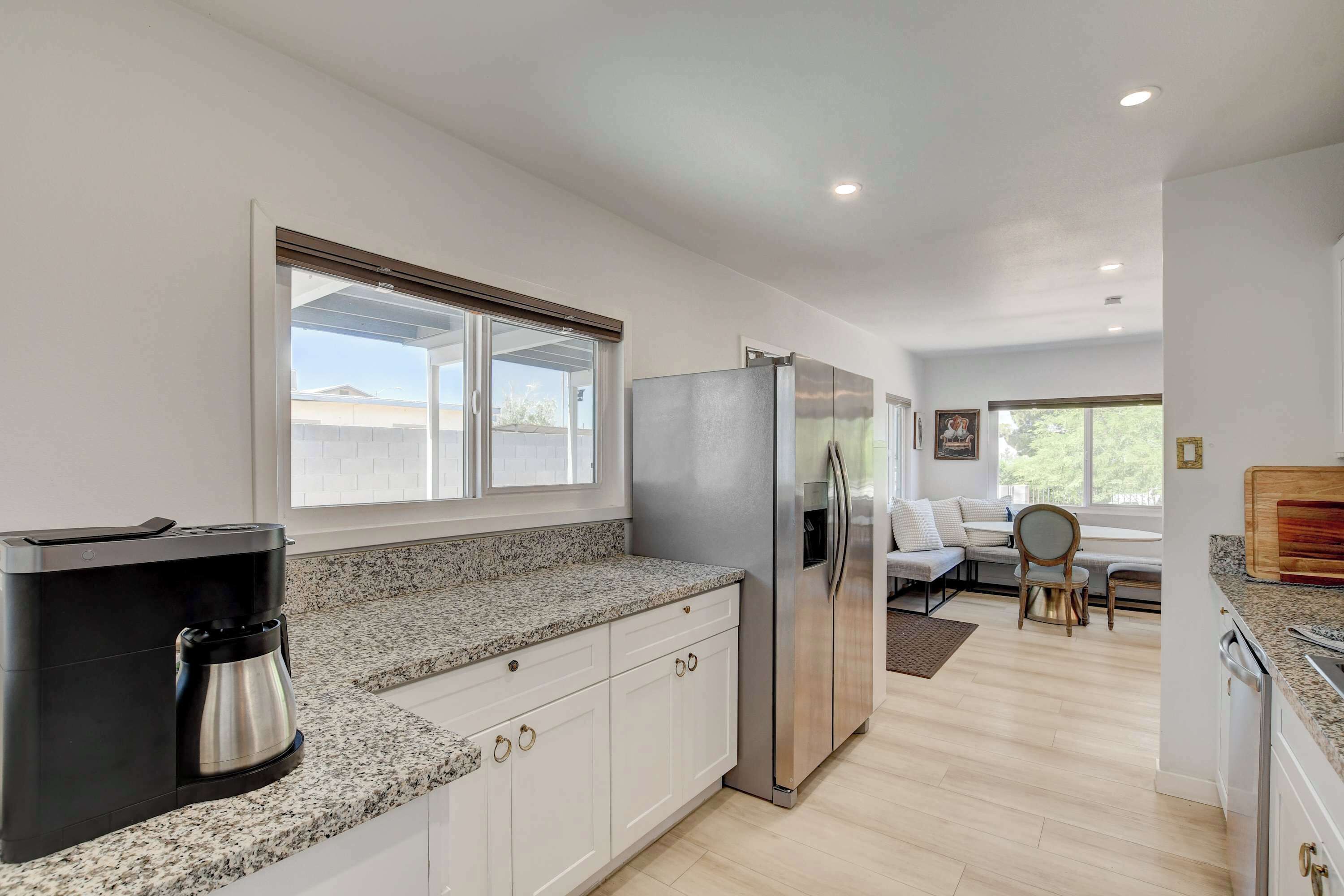A modern kitchen with a built-in coffee maker, a stainless steel refrigerator, and a dining area with a bench and chairs.