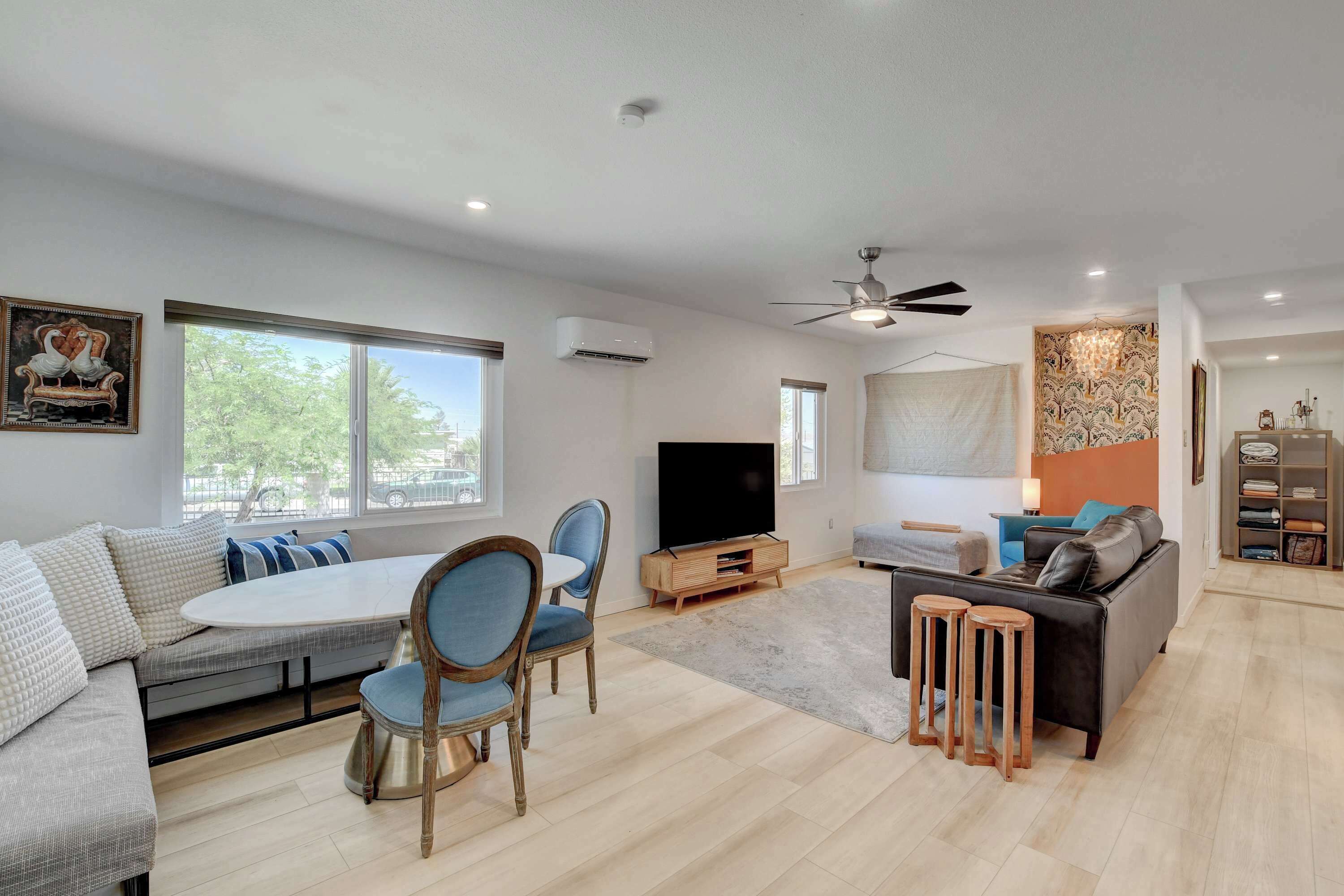 Un salon moderne avec un canapé, des fauteuils, un téléviseur et un ventilateur de plafond.