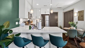 A modern kitchen with a central island, bar stools, and a dining area with a round table and chairs.
