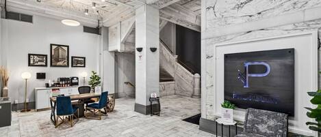 A hotel lobby with a marble floor, a reception desk, a staircase, and a framed sign with the letter 'P'.