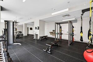 A gym with various exercise equipment, including a squat rack, bench press, and resistance bands. - King Studio / Pool Table + Gym + Free Coffee Bar / 0.3 miles to Fountain Square (Cincinnati)