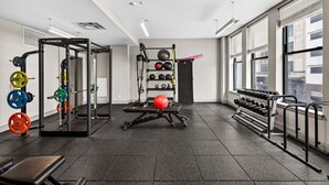 A gym with weightlifting equipment, exercise balls, and dumbbells.