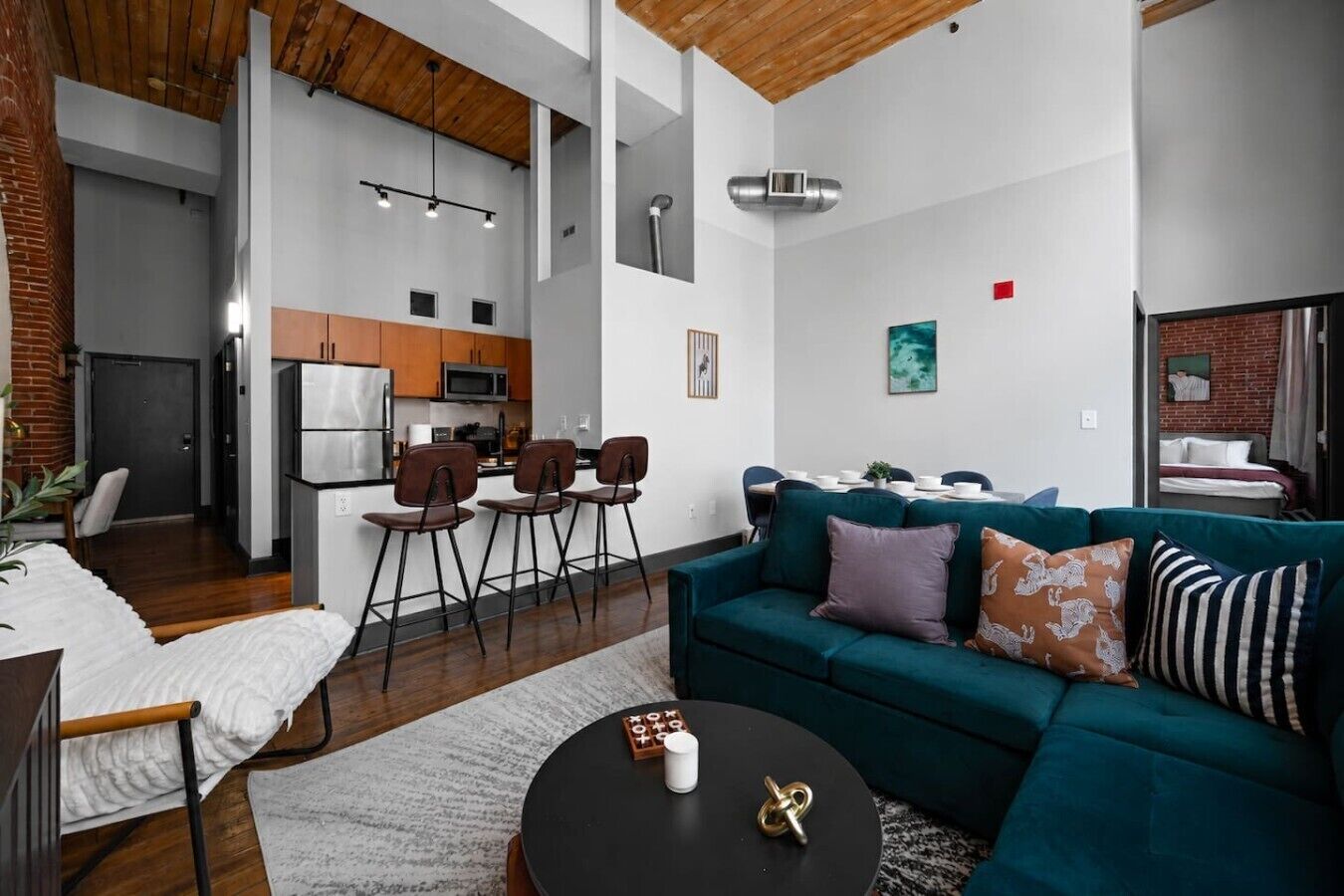 Een moderne woonkamer met een blauwgroene bank, een salontafel en een keuken op de achtergrond.