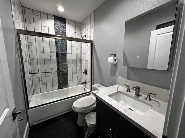 A modern bathroom with a glass-enclosed shower, a toilet, a sink, and a mirror.